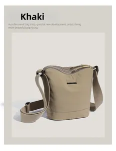 Detail view of khaki nylon bucket bag with BARMAMEREN logo and wide shoulder strap