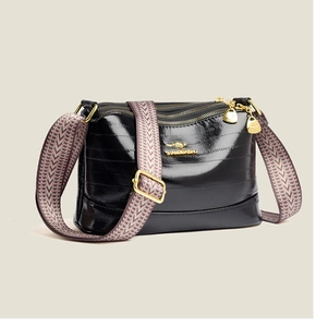 Detail view of black gloss handbag with three zipper compartments and woven strap