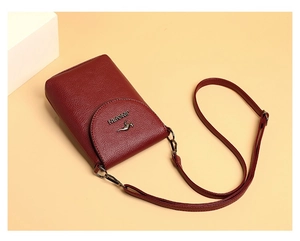 Detail view of wine red lychee leather crossbody bag with kangaroo logo and hardware