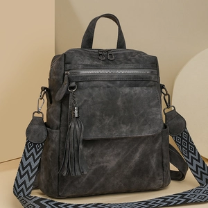 Retro grey canvas backpack with tassel detail and geometric woven strap in studio setting