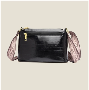 Close-up of black glossy crossbody bag back zip pocket and patterned wide strap