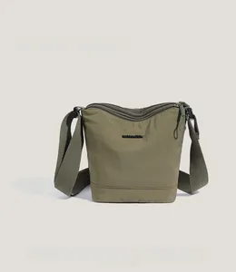 Detail of olive green nylon bucket bag featuring multiple zipper compartments and brand logo