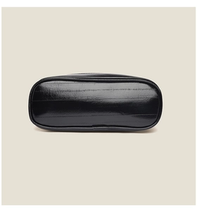 Detailed base view of black glossy faux leather shoulder bag with visible stitching and texture