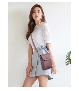 Burgundy pebbled leather crossbody bag with metal kangaroo logo shown on a model