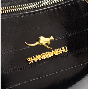 Close-up of black textured leather bag with gold kangaroo logo and metal zipper detail