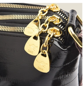Detailed view of triple gold zippers and brand logo on black glossy leather crossbody bag