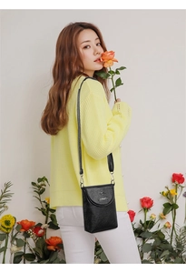 Detail of black lychee texture leather crossbody phone bag with metal kangaroo logo on model