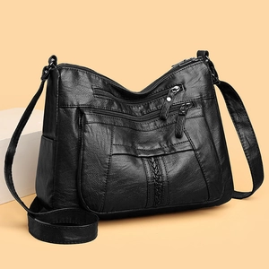 Detail view of the black soft leather crossbody bag with multiple zippers and weave pattern