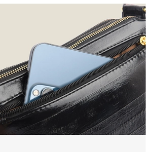 Detail showing a smartphone inside the side pocket of a black crocodile texture handbag