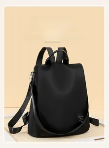 Detail view of black oxford fabric backpack with stylish logo patch and top handle