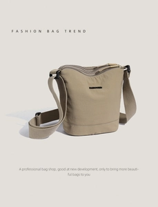 Detail of khaki nylon bucket bag showing soft fabric texture and black logo label