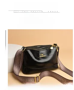 Close-up of black crossbody bag with three zipper compartments and a wide woven strap