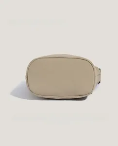 Detailed base of beige nylon bucket bag showing reinforced stitching and oval bottom shape
