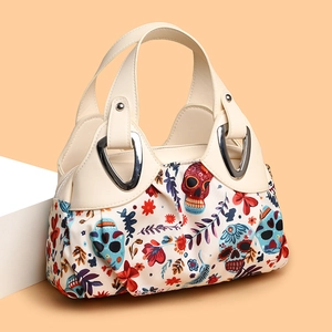 Colorful sugar skull floral handbag with cream handles and silver hardware on orange background