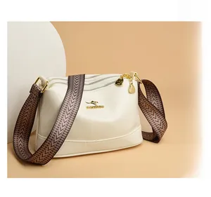 Detail view of cream shoulder bag featuring triple zippers and stylish wavy shoulder strap
