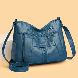 Detail of navy blue soft leather crossbody bag with woven texture and zipper pockets