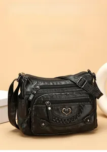 Dettaglio borsa a tracolla in pelle nera con cerniere multiple e logo a cuore