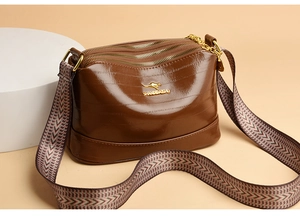 Close-up of brown crocodile pattern shoulder bag with triple zipper pockets and wide strap