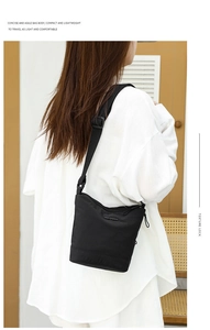 Detail of a lightweight black nylon bucket bag with adjustable strap worn by a model