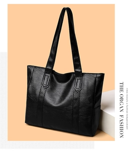 Dettaglio della borsa tote in pelle nera con cuciture verticali e finitura materica
