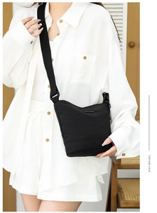 Detail of adjustable wide fabric strap and nylon texture on a black crossbody bucket bag