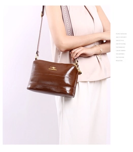 Close-up of brown patent leather crossbody bag with vintage woven shoulder strap and logo