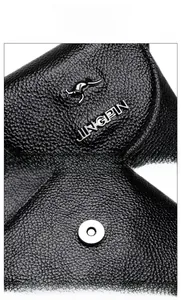 Close-up of black lychee grain leather bag with metal logo and magnetic snap closure