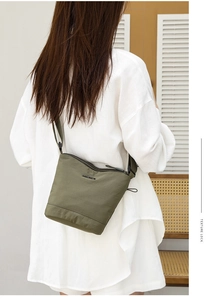 Detail of army green nylon bucket bag featuring adjustable black strap and sleek zip closure