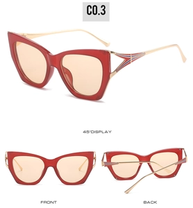 Macro detail of red cat-eye sunglasses with gold metal temples and stripe pattern
