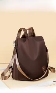 Detail of dark brown waterproof oxford fabric backpack with stylish leather logo patch