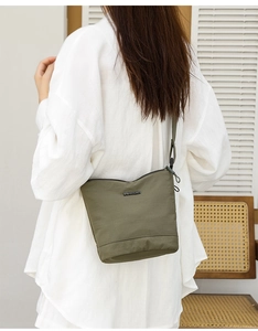 Detail of dark green nylon bucket bag featuring a BAOLANGREN metal logo and shoulder strap