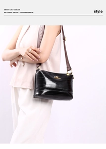 Detail of black glossy crossbody bag with golden kangaroo logo and adjustable strap