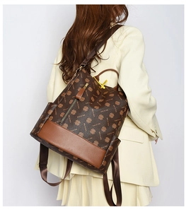 Rear view of a stylish brown monogram backpack worn with a beige suit for city style