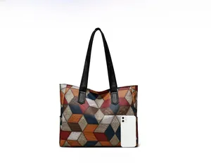 Dettaglio di una borsa tote con motivo geometrico 3D e smartphone per confronto dimensioni