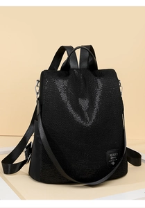 Close-up of black sequined oxford fabric and brand logo plate on anti-theft backpack