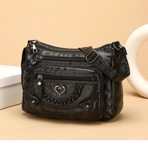 Dettaglio borsa a tracolla nera con tasche a zip e fibbia metallica a forma di cuore