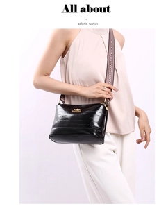 Detail of black glossy shoulder bag featuring golden kangaroo logo and woven strap
