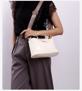 Detailed view of cream leather shoulder bag with colorful geometric woven strap and gold logo