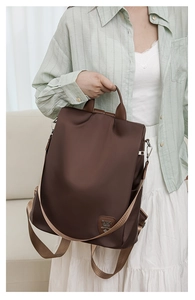 Detail of waterproof dark brown oxford backpack with leather handle and metal accents