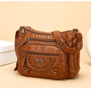 Dettaglio borsa a tracolla marrone con tasche con zip e decorazione in metallo a cuore