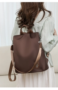Brown oxford anti-theft backpack with rear zip closure and woven straps shown on model