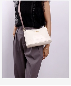 Detailed view of cream leather crossbody bag with adjustable strap on a model