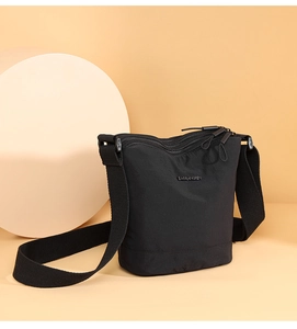Detail of multi-zipper compartments and BAOMANREN metal logo on black nylon bucket bag