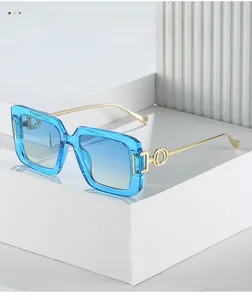 Detail of square blue sunglasses with gold metal temples on white geometric blocks