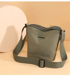 Detailed close-up of olive green nylon bucket bag with layered zippers and brand logo