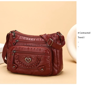 Dettaglio borsa a tracolla rosso vino con tasche a zip e logo metallico a cuore