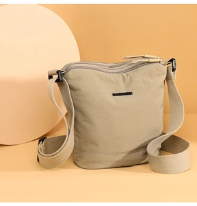 Detailed view of the khaki nylon crossbody bag featuring a triple-zipper storage design