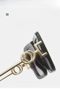 Close-up of black acetate sunglasses frame with golden metal temples and circular logo