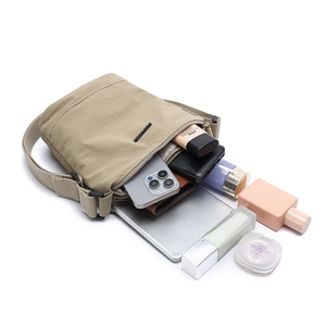 Khaki nylon crossbody bag with multiple zippers showing large storage capacity for gadgets