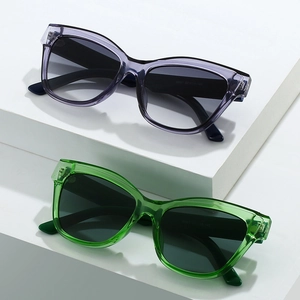 Occhiali da sole cat-eye moderni con montature trasparenti viola e verdi su cubi